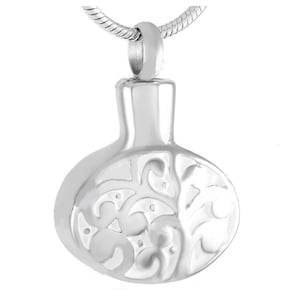 May include: Silver tone pendant necklace with a round, engraved urn-shaped charm. The charm has a detailed floral design.