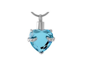 May include: A silver heart-shaped pendant necklace with a light blue crystal and small clear stones around the edge.