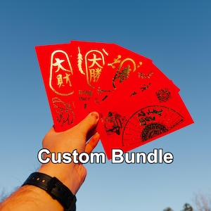 May include: A hand holding a bundle of red envelopes with gold Chinese characters and designs. The text "Custom Bundle" is displayed in white. The background is a clear blue sky.