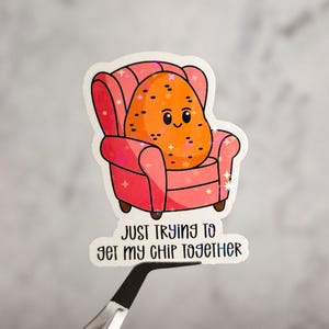 Puede incluir: Una pegatina con una patata de dibujos animados sentada en un sillón rosa. El texto debajo dice "Just trying to get my chip together."