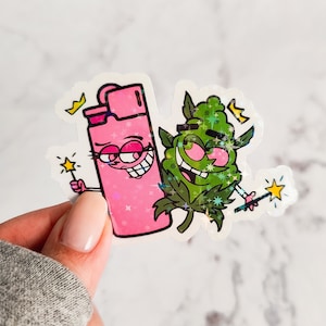 May include: A pink lighter and a green marijuana leaf with cartoon faces and glitter accents. Both characters are holding a magic wand.
