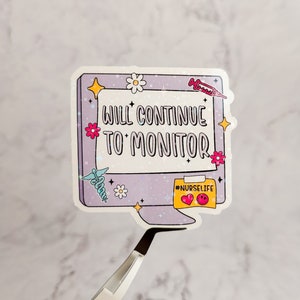 May include: A pink and purple computer monitor sticker with the text "WILL CONTINUE TO MONITOR" and the hashtag "#NURSELIFE". The sticker has a glittery finish and features a variety of colorful flowers and stars.