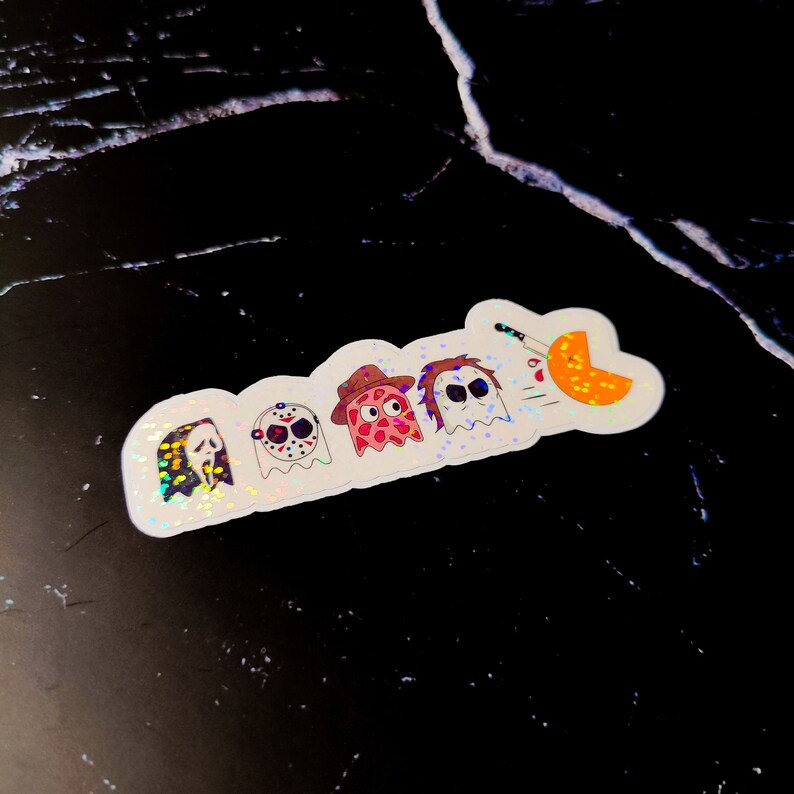 K&ouml;nnte beinhalten: Ein holografischer Aufkleber mit Cartoon-Versionen von Horrorfilmfiguren. Der Aufkleber zeigt Ghostface, Jason Voorhees, einen rosa Geist mit Hut, Michael Myers und einen Geist, der einen K&uuml;rbis mit einem Messer ersticht.
