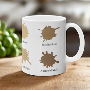 May include: White ceramic mug with brown coffee stain graphics. The mug has the text "Builders Brew" and "A Drop of Milk" printed on it.