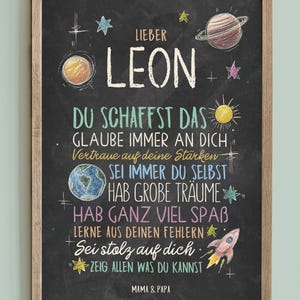 May include: A black chalkboard with white and colorful chalk writing. The chalkboard has a wooden frame and says "Lieber Leon" at the top. The text on the chalkboard reads: "Du schaffst das. Glaube immer an dich. Vertraue auf deine St&auml;rken. Sei immer du selbst. Hab gro&szlig;e Tr&auml;ume. Hab ganz viel Spa&szlig;. Lerne aus deinen Fehlern. Sei stolz auf dich. Zeig allen was du kannst. Mama & Papa."