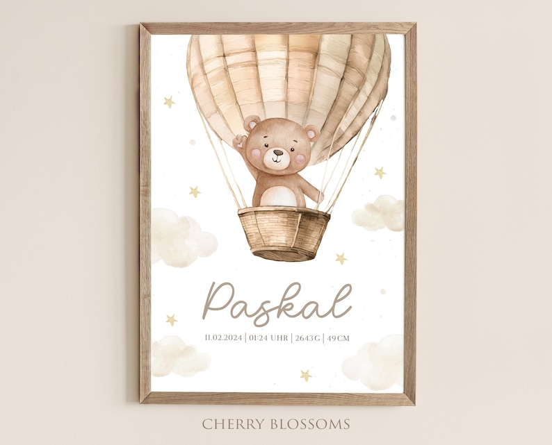 May include: A framed watercolor print featuring a teddy bear in a hot air balloon. The bear is in a woven basket, with the name "Paskal" below. The print includes the date, time, weight, and height in centimeters, with the text "Cherry Blossoms" at the bottom.