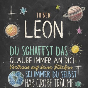 May include: A black chalkboard with white chalk writing. The text says "Lieber Leon", "Du schaffst das", "Glaube immer an dich", "Vertraue auf deine St&auml;rken", "Sei immer du selbst", and "Hab gro&szlig;e Tr&auml;ume". The chalkboard is decorated with drawings of stars, planets, and a sun.