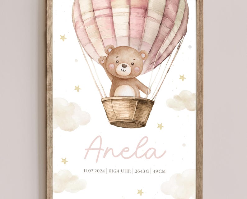 May include: A framed watercolor print featuring a teddy bear in a hot air balloon. The balloon is pink and white, and the bear is in a woven basket. The print includes the name "Anela" and other details.