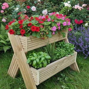May include: A two-tiered wooden planter filled with vibrant red and pink flowers and green herbs. The planter is set in a lush garden with a backdrop of colorful roses and greenery, creating a natural aesthetic.