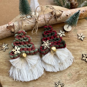 May include: Two handmade Christmas tree ornaments with red and green yarn, white yarn beards, and wooden snowflake accents. The ornaments are hanging from a birch log with small artificial Christmas trees.