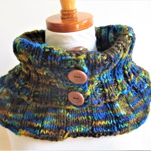 May include: A brown, blue, and green knitted cowl with three brown buttons.