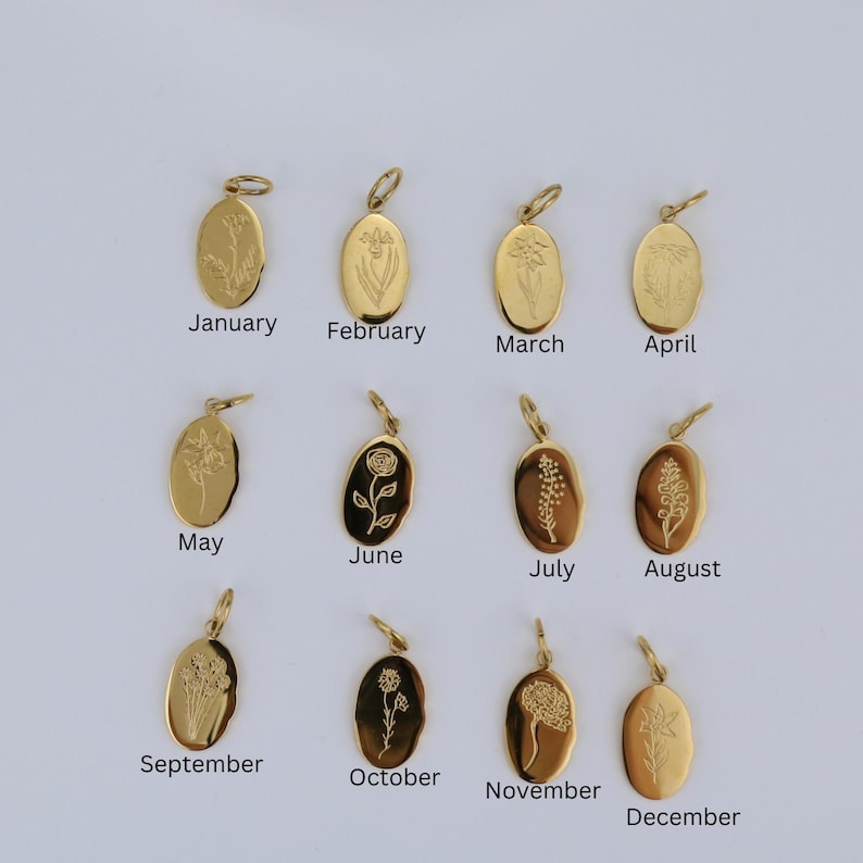 K&ouml;nnte beinhalten: Eine Sammlung von zw&ouml;lf goldfarbenen, ovalen Anh&auml;ngern, die jeweils mit einem anderen Blumendesign und dem Namen eines Monats graviert sind: Januar, Februar, M&auml;rz, April, Mai, Juni, Juli, August, September, Oktober, November und Dezember. Die Anh&auml;nger haben eine kleine Schlaufe.