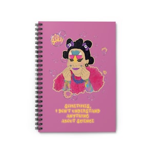 May include: A pink spiral notebook with a cartoon illustration of a person with colorful makeup and hair, surrounded by bubbles. The text "Sometimes, I don't understand anything about science" is printed below the illustration.