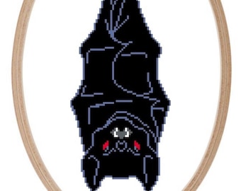 May include: A black bat with red eyes hanging upside down in a wooden embroidery hoop.