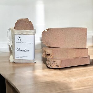 May include: A bar of handmade Cashmere Cream soap, 120 ml (4 oz), in a white muslin bag with the text "Z&L Artisanal Skincare & Candle Co.". The soap is a light brown color and has a rough texture.