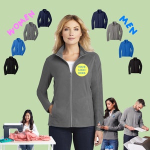 May include: A gray fleece jacket with a zipper closure and a yellow circle with the text "YOUR LOGO HERE" on the left chest. The jacket is shown on a model with a variety of other jackets in different colors in the background.