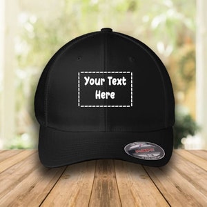 May include: Black mesh back baseball cap with a black front panel. The front panel has a white rectangular patch with the text "Your Text Here" in a white, rounded font.