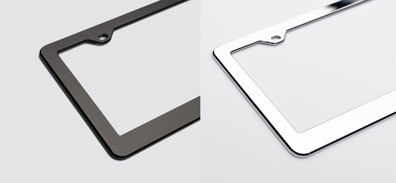 May include: Two license plate frames, one black and one chrome. Both frames have a rounded edge and a hole in the top center.