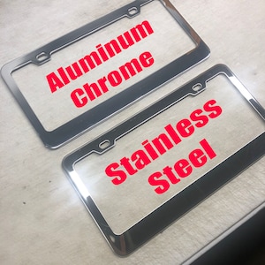 May include: Two chrome license plate frames. The top frame says "Aluminum Chrome" and the bottom frame says "Stainless Steel".