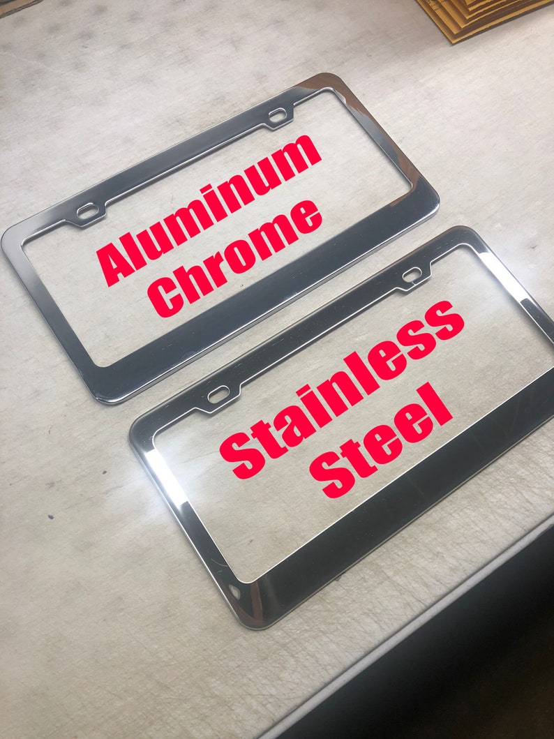 May include: Two chrome license plate frames. The top frame says "Aluminum Chrome" and the bottom frame says "Stainless Steel".