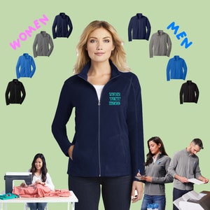 May include: A navy blue fleece jacket with a zipper closure and a contrasting zipper pull. The jacket has a stand-up collar and two front pockets. The text "YOUR TEXT HERE" is embroidered on the left chest of the jacket.