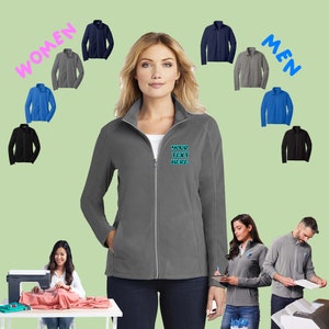 May include: A gray fleece jacket with a zipper closure. The jacket has a stand-up collar and two front pockets. The text "YOUR TEXT HERE" is embroidered on the front of the jacket.