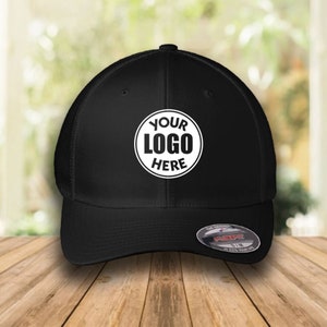 Peut inclure: Casquette de baseball noire en maille et sergé avec un logo circulaire blanc qui dit "YOUR LOGO HERE".