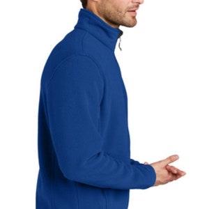 May include: A royal blue fleece jacket with a zipper closure. The jacket has a stand-up collar and a zippered pocket on the left side.