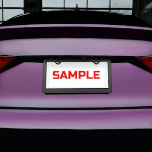 May include: A purple car with a black license plate frame that says "SAMPLE" in red letters.