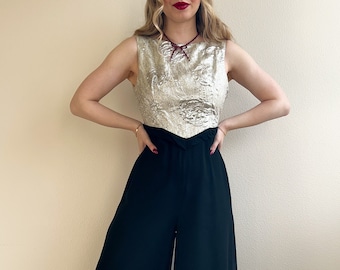 May include: A black and silver jumpsuit with a wide-leg silhouette. The top is a silver brocade fabric with a sweetheart neckline. The bottom is a solid black fabric.