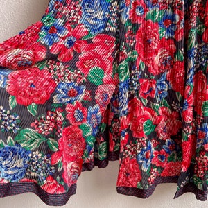 K&ouml;nnte beinhalten: Schwarze, gefaltete Hose mit rotem, blauem und gr&uuml;nem Blumendruck. Die Hose hat einen schwarzen und wei&szlig;en Tupfenbesatz.