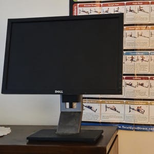 May include: A black Dell computer monitor with a rectangular screen and a sturdy, adjustable stand. The monitor features a thin black bezel with the Dell logo centered at the bottom edge. The stand has a silver and black finish with a base.