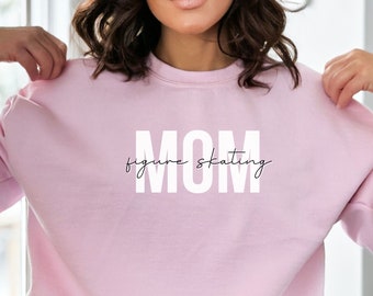 May include: Pink sweatshirt with the text "MOM figure skating" in white letters.