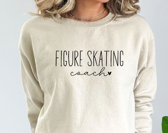May include: A beige sweatshirt with the text "FIGURE SKATING coach" in black lettering and a small black heart.