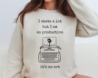 May include: A beige sweatshirt with the text "I skate a lot but I am so productive it's an art" and a black and white illustration of a typewriter with a figure skating on a piece of paper.