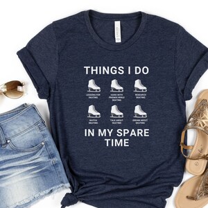 May include: A navy blue t-shirt with white text that reads "Things I do" and lists activities related to ice skating. The text "In my spare time" is also printed on the shirt.