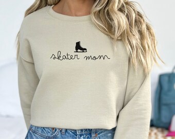 May include: A beige sweatshirt with a black ice skate graphic and the text "skater mom" printed on the front.