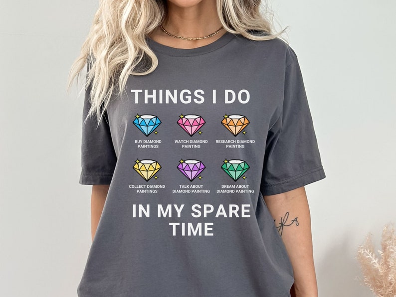 May include: A gray t-shirt with the text "THINGS I DO" and a list of activities related to diamond painting. The activities include: buy diamond paintings, watch diamond painting, research diamond painting, collect diamond paintings, talk about diamond painting, and dream about diamond painting. The text "IN MY SPARE TIME" is below the list.