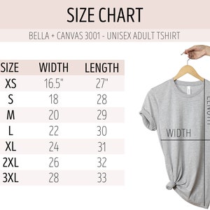 May include: Size chart for a unisex adult t-shirt, showing width and length measurements in inches for sizes XS to 3XL. The chart shows a gray t-shirt hanging on a wooden hanger.