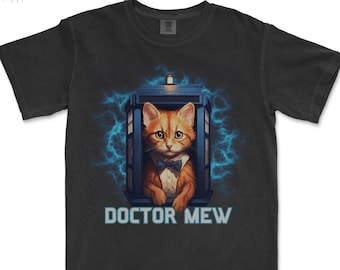 Puede incluir: Una camiseta negra con un gráfico de un gato naranja con pajarita de pie en una cabina de policía azul. El texto "DOCTOR MEW" está impreso debajo de la imagen.