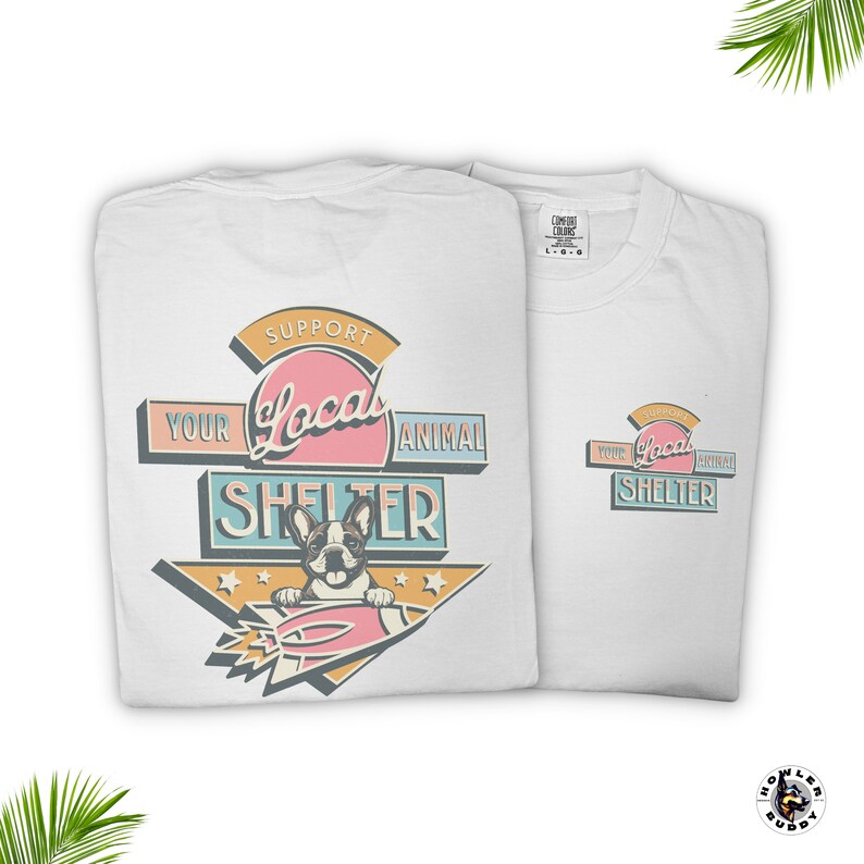 May include: Two white t-shirts with a colorful graphic that reads "Support Your Local Animal Shelter." The design features a cartoon dog on a rocket. The shirts have a crew neck and short sleeves.