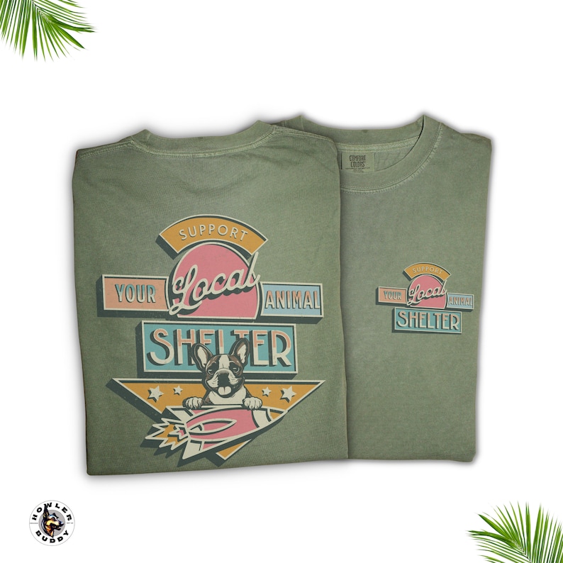 May include: Two olive green t-shirts with a graphic that reads "Support Your Local Animal Shelter." The design features a French bulldog in a rocket ship. The shirts are made of a soft material.