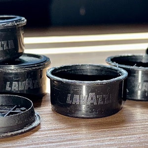 May include: Five black plastic coffee pods with the word "Lavazza" printed on them.