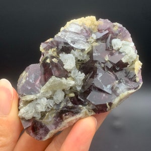 May include: A cluster of purple fluorite crystals with a light brown matrix. The crystals are translucent and have a glassy lustre. Some of the crystals have a slight green tint.
