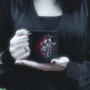 May include: Black ceramic mug with a graphic of a red and blue heart with the word "SYSTEM" printed on it.