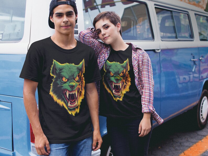 May include: Two people wearing black t-shirts with a green and yellow wolf graphic print. The wolf has sharp teeth and a menacing expression.