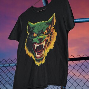 May include: Black t-shirt with a green and yellow wolf graphic. The wolf has a menacing expression with sharp teeth and glowing eyes.
