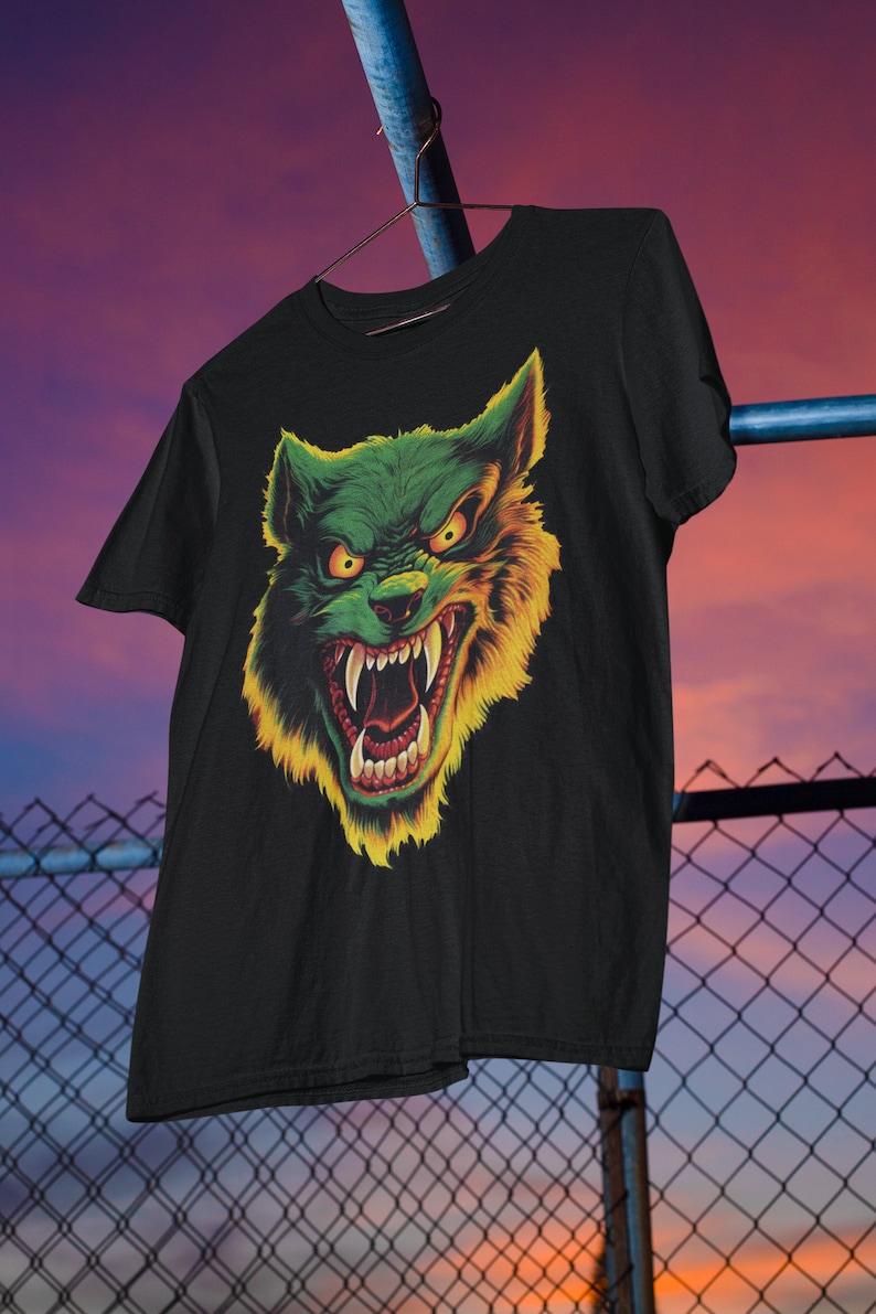 May include: Black t-shirt with a green and yellow wolf graphic. The wolf has a menacing expression with sharp teeth and glowing eyes.