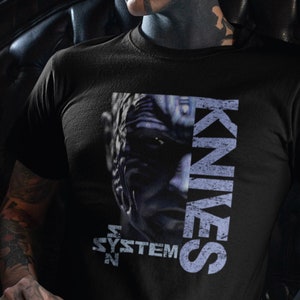 May include: Black t-shirt with a graphic print of a face and the text "KNIVES OUT SYSTEM"