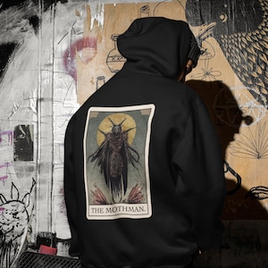 May include: Black hoodie featuring a graphic of a winged creature with the text "THE MOTHMAN."